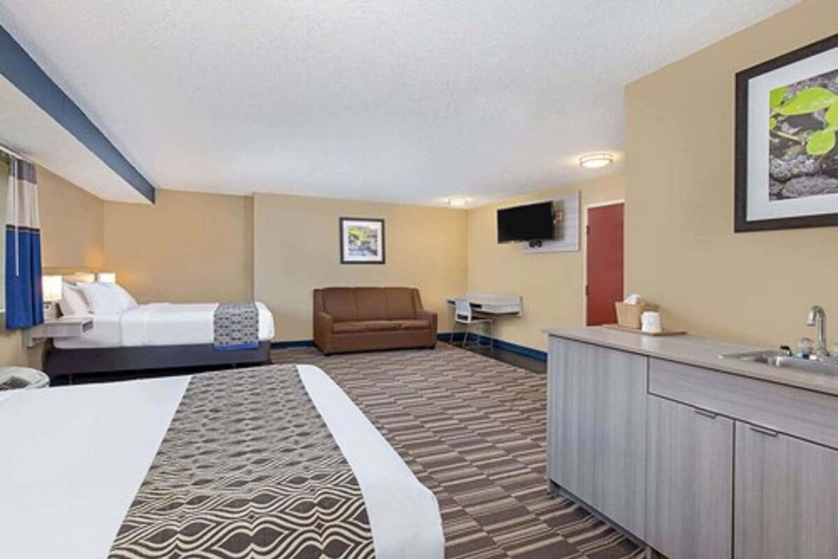 A hotel room with a bed, a sofa, a desk, and a bathroom.