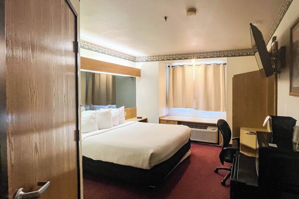 Hotellihuone, jossa on sänky, työpöytä, tuoli ja seinälle asennettu televisio.