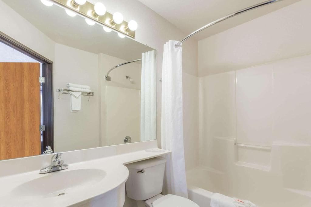 Un baño con lavamanos, espejo y cortina de ducha.