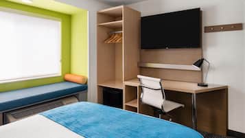 A hotel room with a bed, a desk with a chair, a television, a wardrobe, and a window.