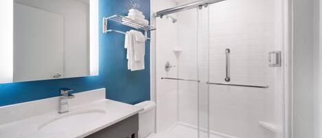 Une salle de bain avec un lavabo blanc, des toilettes et une douche à parois de verre.