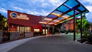 A hotel entrance with a modern design, featuring a glass canopy and a stone facade.