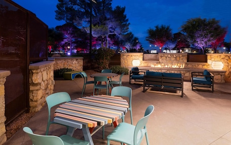 An outdoor patio area with stone walls, a fire feature, and seating arrangements.