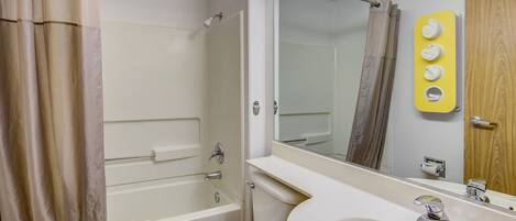 A bathroom with a bathtub, toilet, sink, and a mirror.