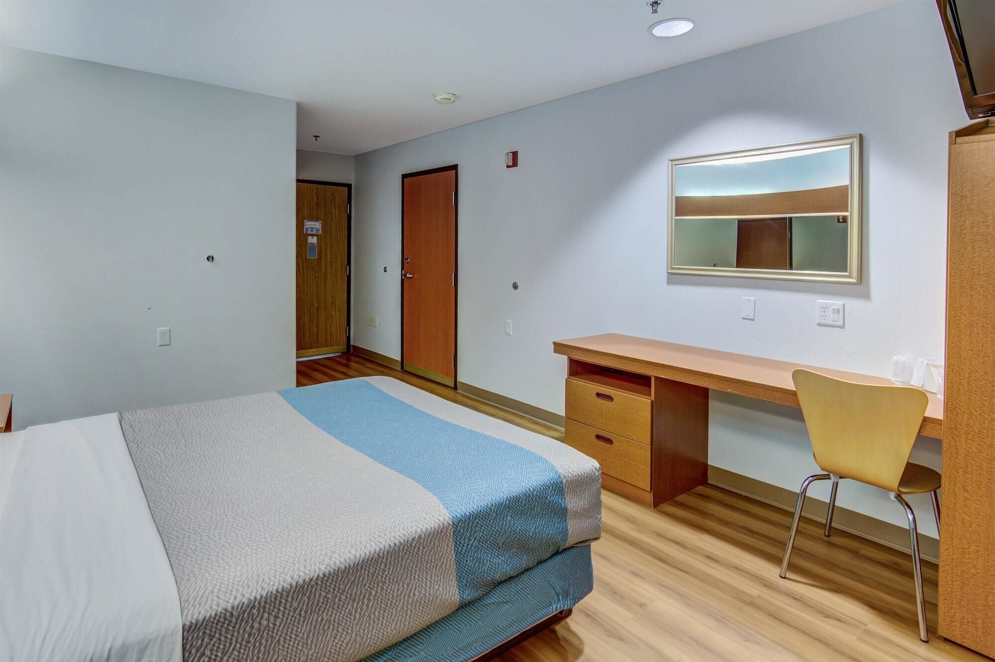 A bedroom with a bed, a desk, and a chair.