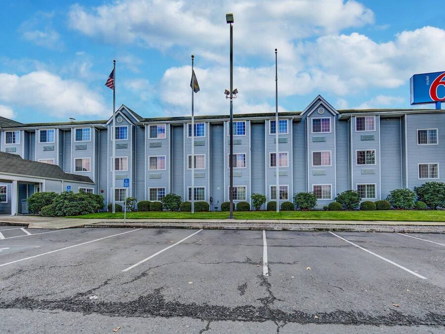 A motel with a parking lot and a building with multiple windows and a flag.