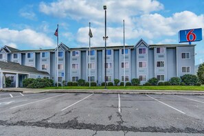 A motel with a parking lot and a building with multiple windows and a flag. - Motel 6 Sutherlin, OR (Sutherlin)