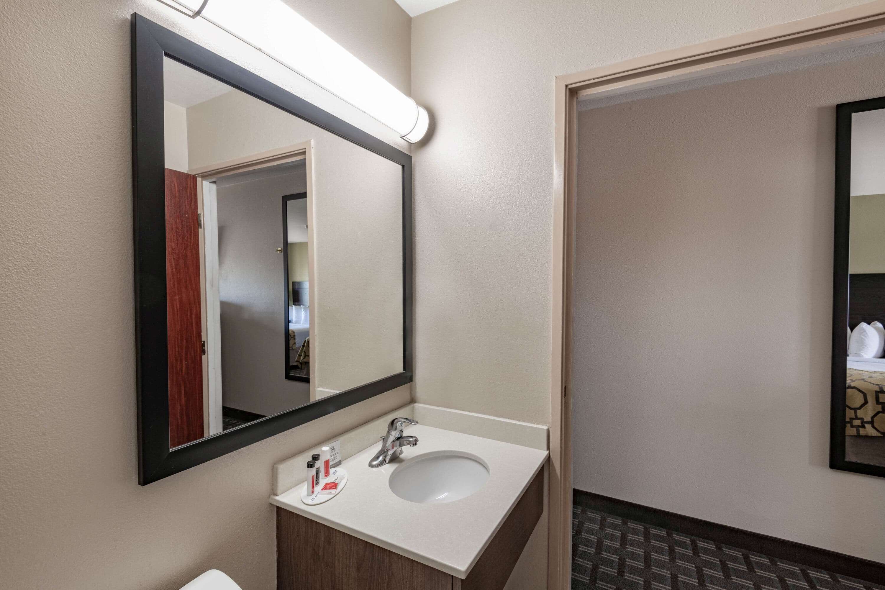 A hotel bathroom with a white sink, a mirror, and a toilet.