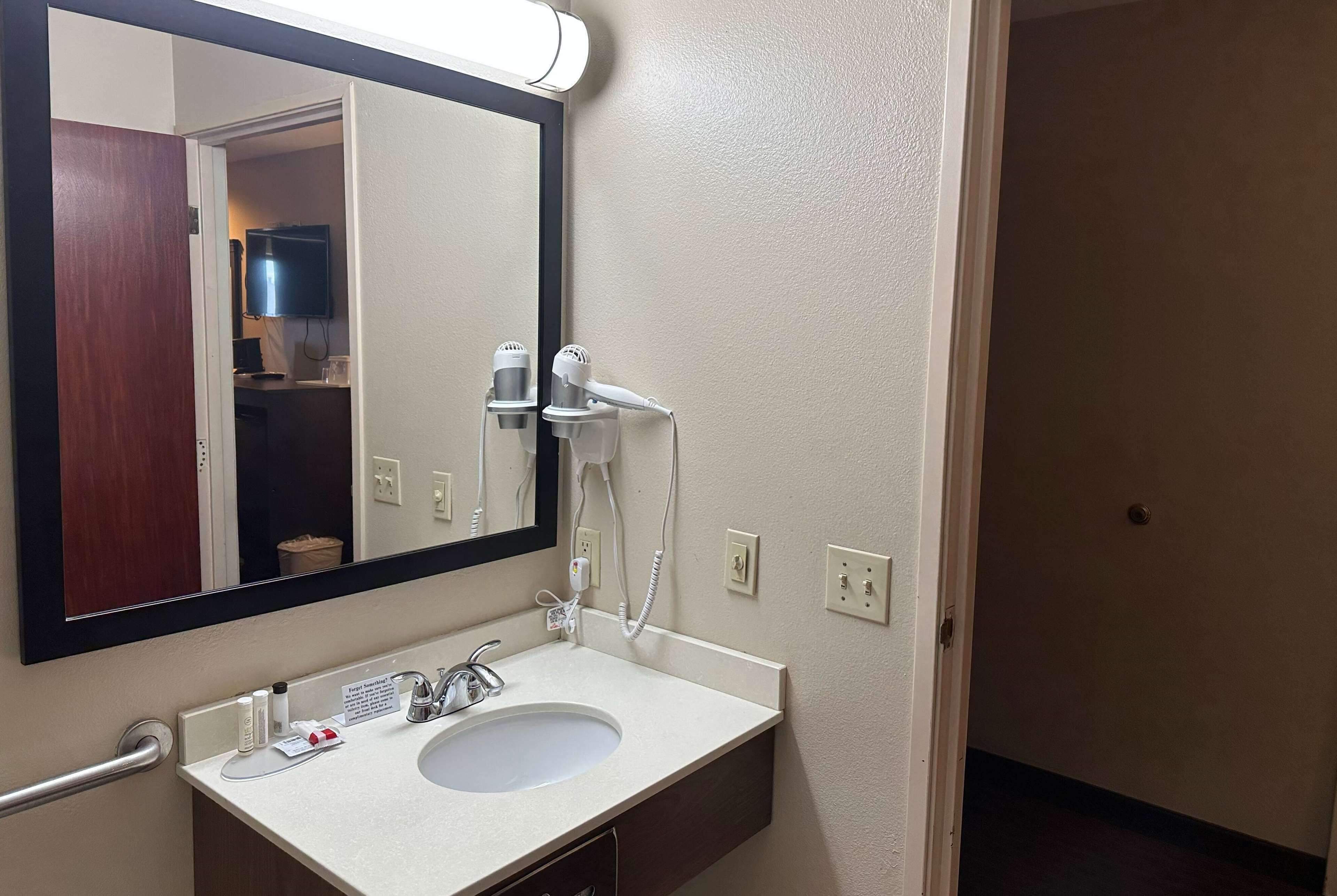 A bathroom with a white sink, a mirror, a hairdryer, and a towel rack.