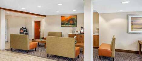 A hotel lobby with seating, an ATM, and a coffee station.
