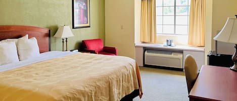 Una habitación de hotel con una cama grande, un escritorio, una silla, una ventana con cortinas y un cuadro en la pared.