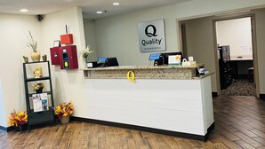 A reception desk with a 'Quality by Choice Hotels' sign, a red information kiosk, and a 'Welcome' sign. - Quality Inn & Suites Prestonsburg next to Mountain Arts Center (Prestonsburg)