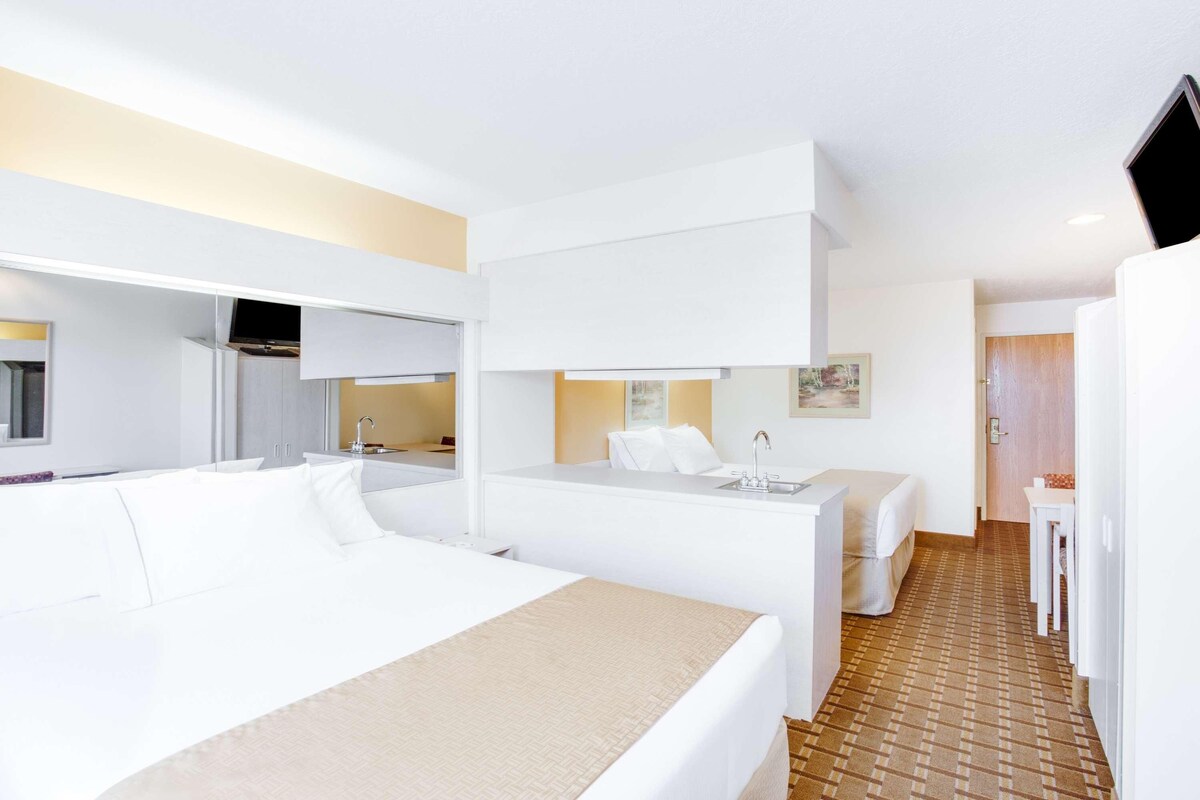 Una habitación de hotel con una cama grande, una cama más pequeña, un escritorio y un baño.