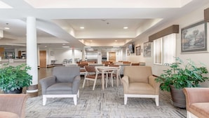 A spacious lobby with multiple seating areas, a reception desk, and framed artwork on the walls.