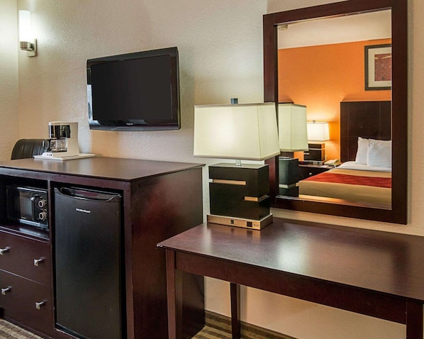 A hotel room with a desk, a television, a bed, and a mirror reflecting the room. - Econo Lodge Inn & Suites Natchitoches (Natchitoches)