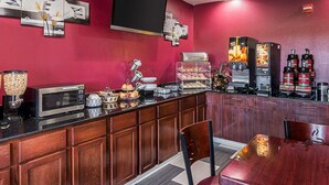 A hotel room with a wooden cabinet, a microwave, a coffee machine, and a flat-screen TV mounted on the wall.
