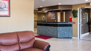 A lobby with a brown leather sofa, a reception desk, and a fire extinguisher.