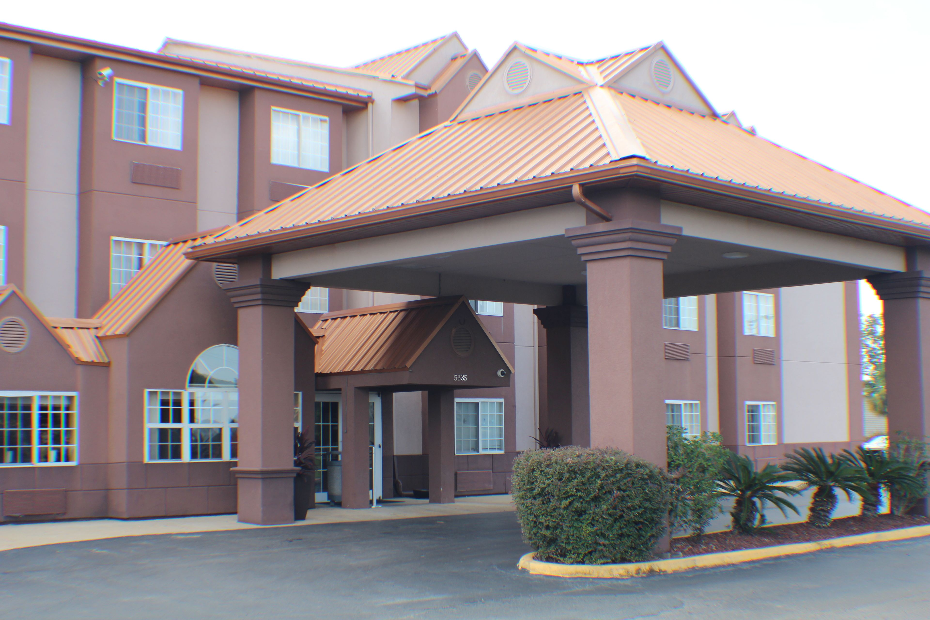 A multi-story hotel with a covered entrance, large windows, and a parking lot.