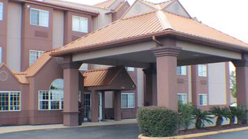 A multi-story hotel with a covered entrance, large windows, and a parking lot.