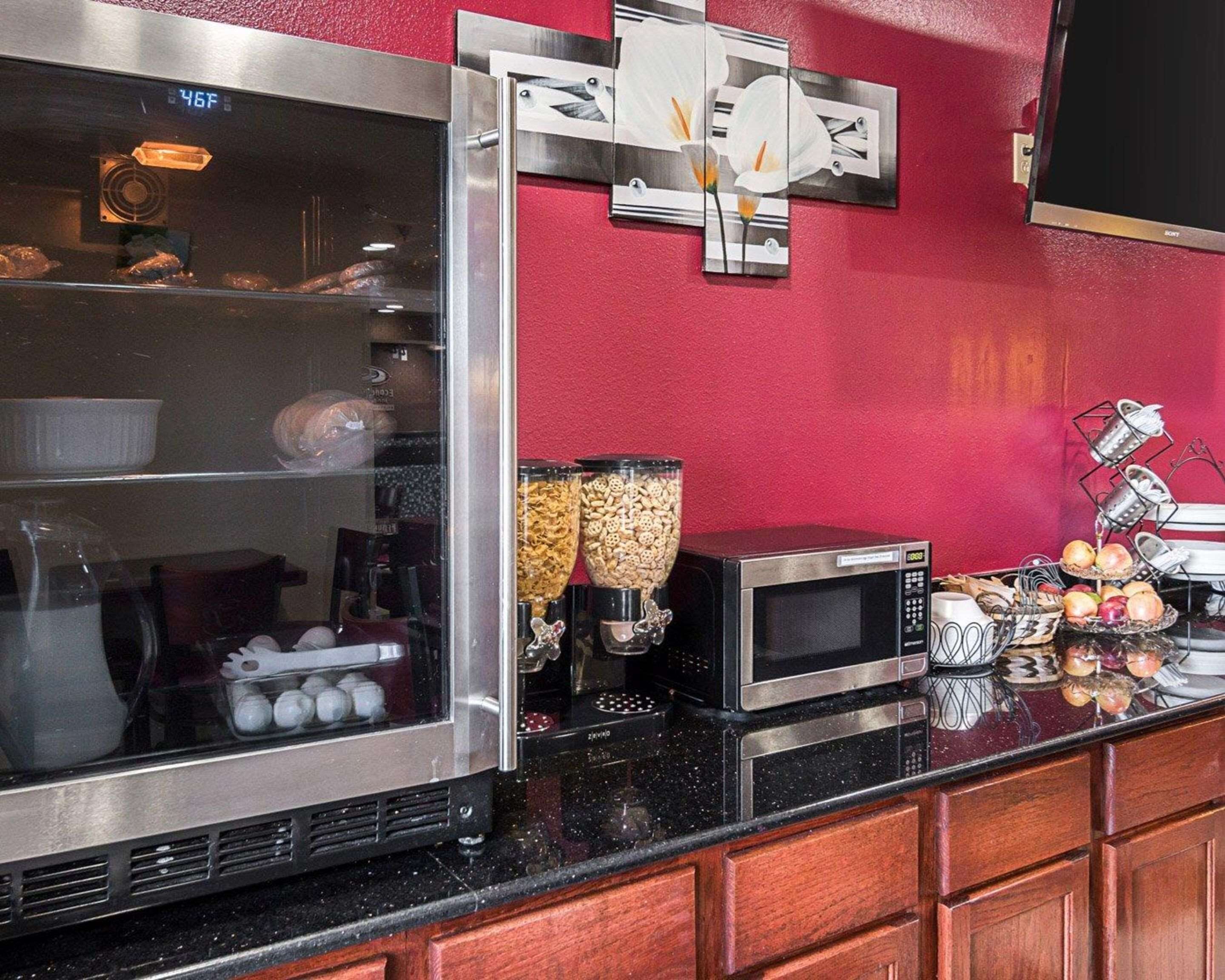 Una cocina con un refrigerador de acero inoxidable, un microondas y una cafetera. Hay frascos con aperitivos y condimentos en la encimera.