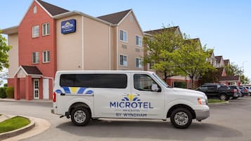 Una camioneta blanca estacionada frente a un edificio Microtel Inn & Suites.