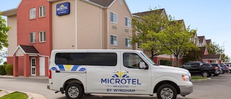 A white van parked in front of a Microtel Inn & Suites building.
