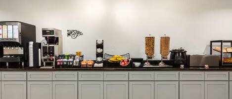 A kitchen area with a coffee machine, a clock, and various kitchen appliances.