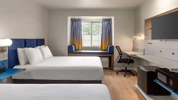 A hotel room with a bed, a desk, a chair, a TV, and a microwave.