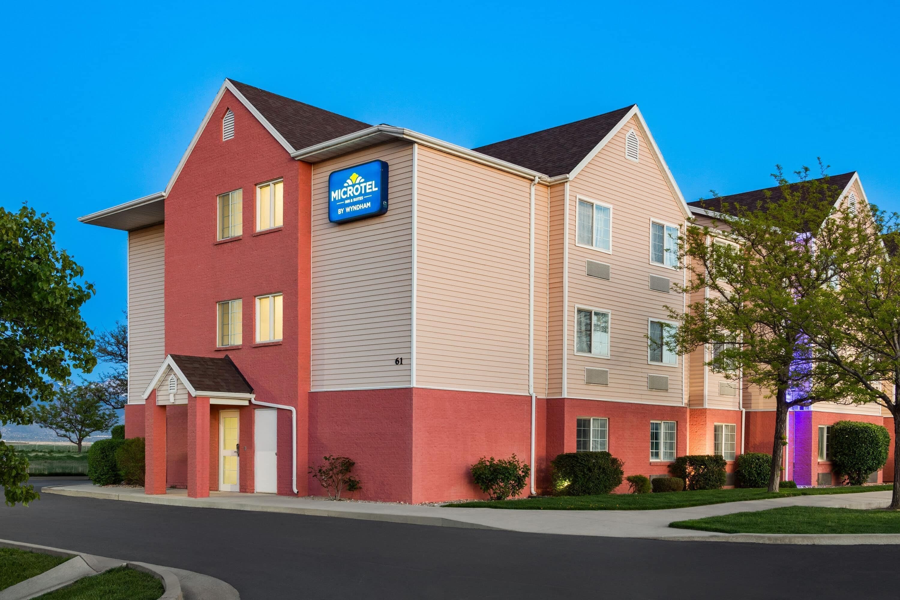 A Microtel hotel with a red and beige facade, multiple windows, and a well-maintained lawn.