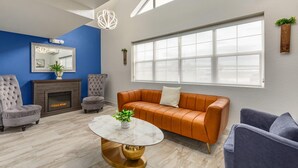 A living room with a fireplace, a large window, and a blue accent wall. - Microtel Inn & Suites by Wyndham Salt Lake City Airport (Salt Lake City)