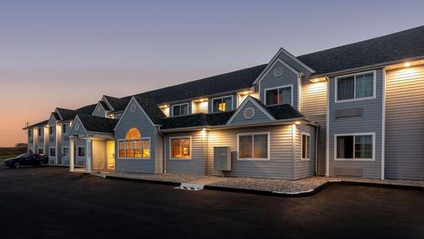 Een rij gelijkvloerse huizen met aaneengebouwde garages, een geplaveid pad en een heldere lucht.