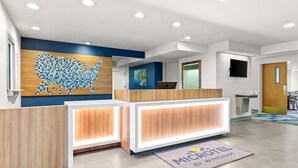 Een receptiebalie met een digitale kaart van de VS, een houten receptiegedeelte en een bordje met 'MICROHOTEL BY JYNDHAMI'.