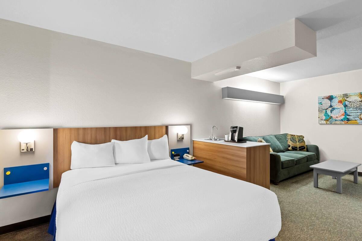 Ein Hotelzimmer mit einem großen Bett, einem Schreibtisch mit Stuhl, einer Couch und einem kleinen Tisch.