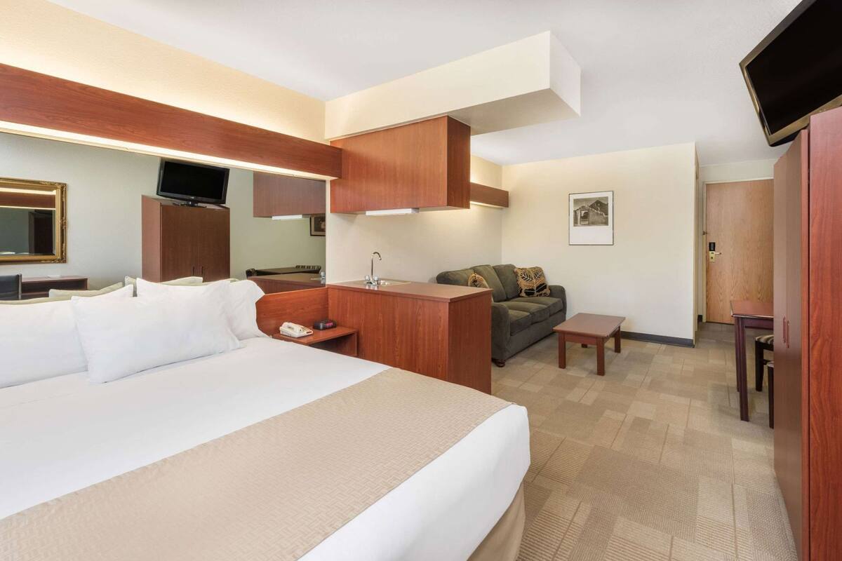 Ein Hotelzimmer mit Bett, Schreibtisch, Sofa, Fernseher und Spiegel.