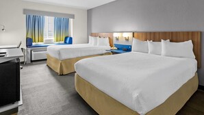 Een hotelkamer met twee bedden, een bureau, een stoel en een raam met gordijnen.