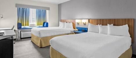 Habitación de hotel con dos camas, un escritorio, una silla y un ventanal con cortinas.