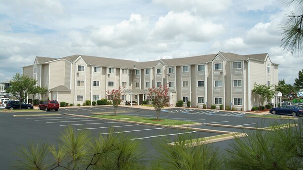 A multi-story hotel with a parking lot in front. - Expo Inn Hotel (Tulsa)