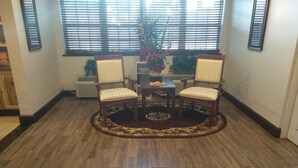 A room with a wooden floor, two chairs with cushioned seats, a small table, and a decorative rug. - Expo Inn Hotel (Tulsa)