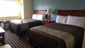 A hotel room with two beds, a desk, and a chair.