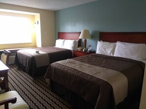 A hotel room with two beds, a desk, and a chair.
