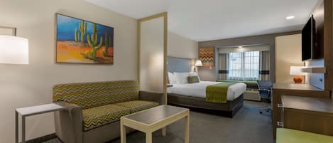 Une chambre d’hôtel avec un lit, un canapé, un bureau, une chaise et un téléviseur.