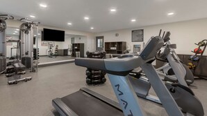 Ein modernes Fitnessstudio mit Cardiogeräten, Krafttrainingsgeräten und einer Spiegelwand.