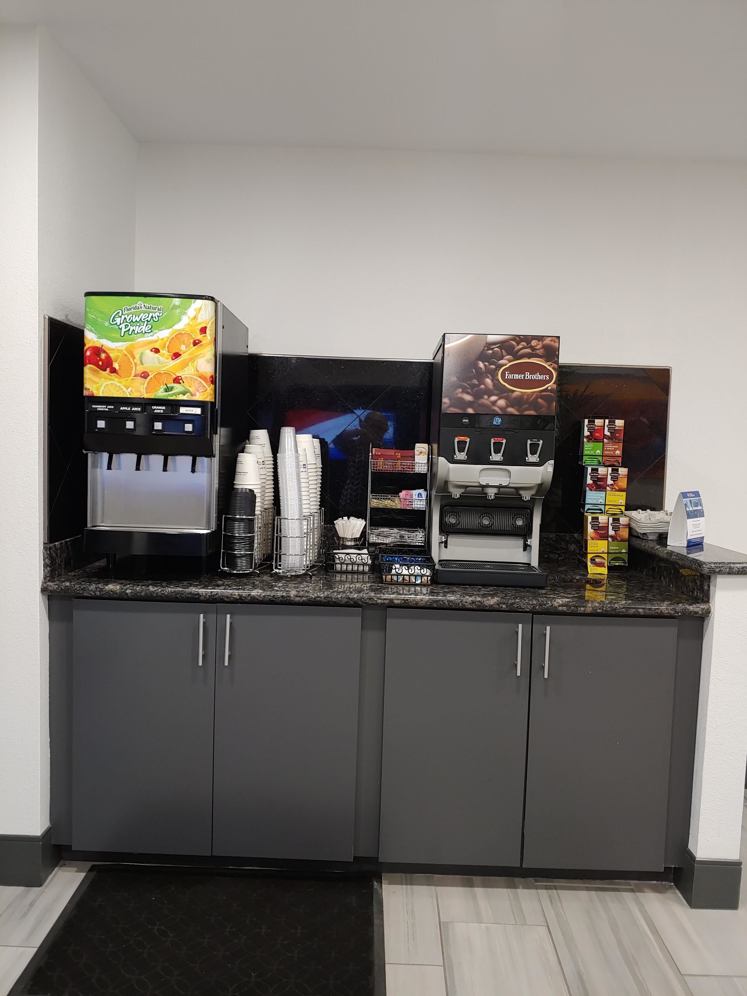 A kitchenette with a coffee machine, a juice dispenser, and a coffee maker.