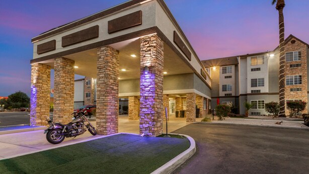 Ein Hotel mit steinverkleideter Fassade, ein Motorrad vor der Tür und eine Palme in der Nähe.