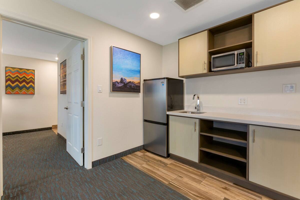 A compact kitchen with a refrigerator, microwave, and a sink.