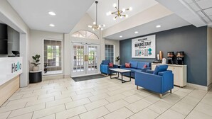 A reception area with a 'Hello' sign, blue sofas, a coffee station, and a 'Welcome to Mainstay Suites' sign. - MainStay Suites Raleigh North (Raleigh)
