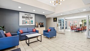 A modern hotel lobby with blue sofas, a coffee station, and a dining area. - MainStay Suites Raleigh North (Raleigh)