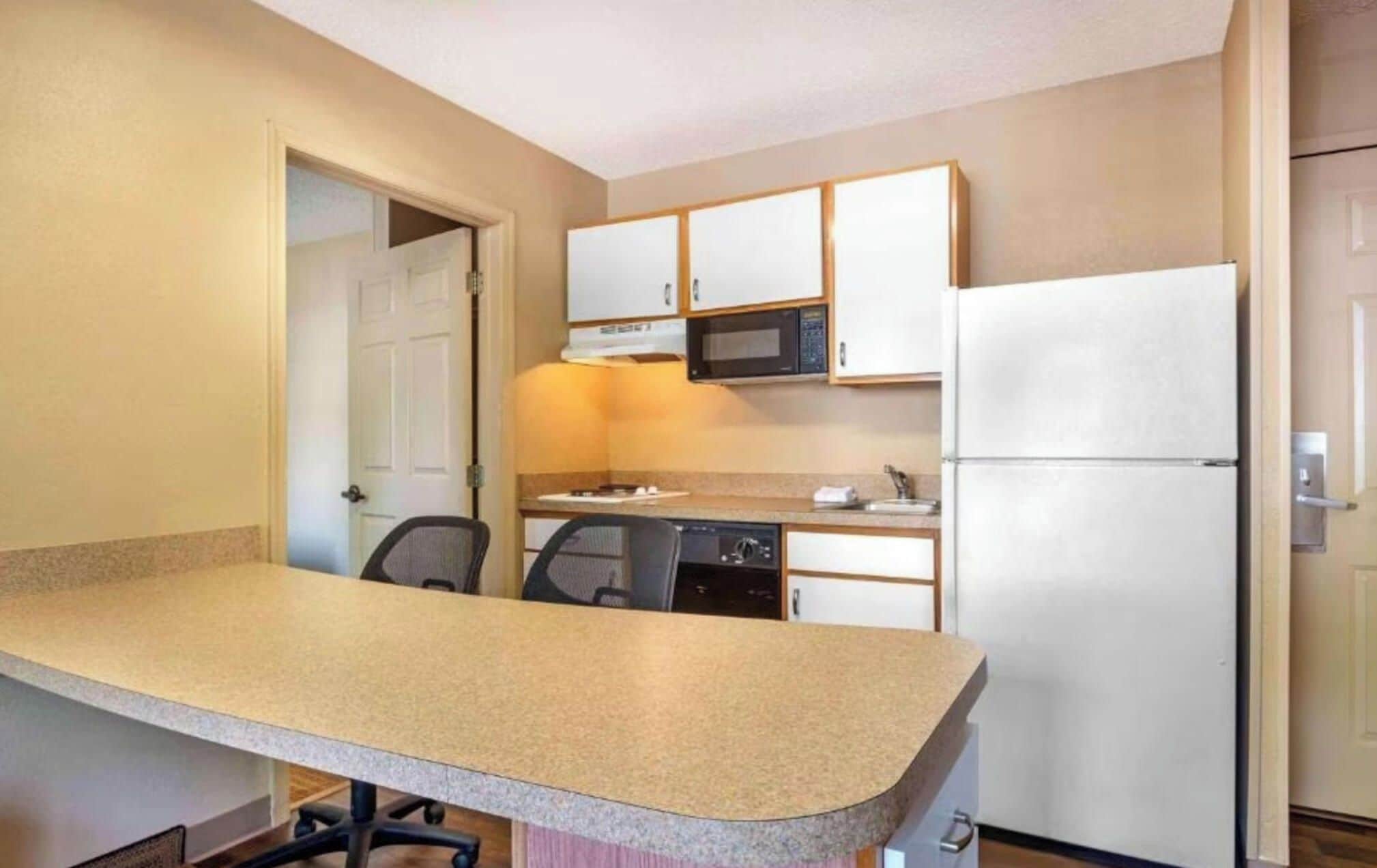 A compact kitchen with a granite countertop, a microwave, a refrigerator, and a dishwasher.
