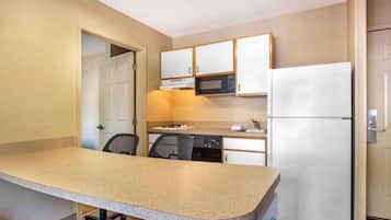 A compact kitchen with a granite countertop, a microwave, a refrigerator, and a dishwasher.