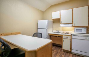 Compact kitchen with a dining area, featuring a refrigerator, microwave, and sink.